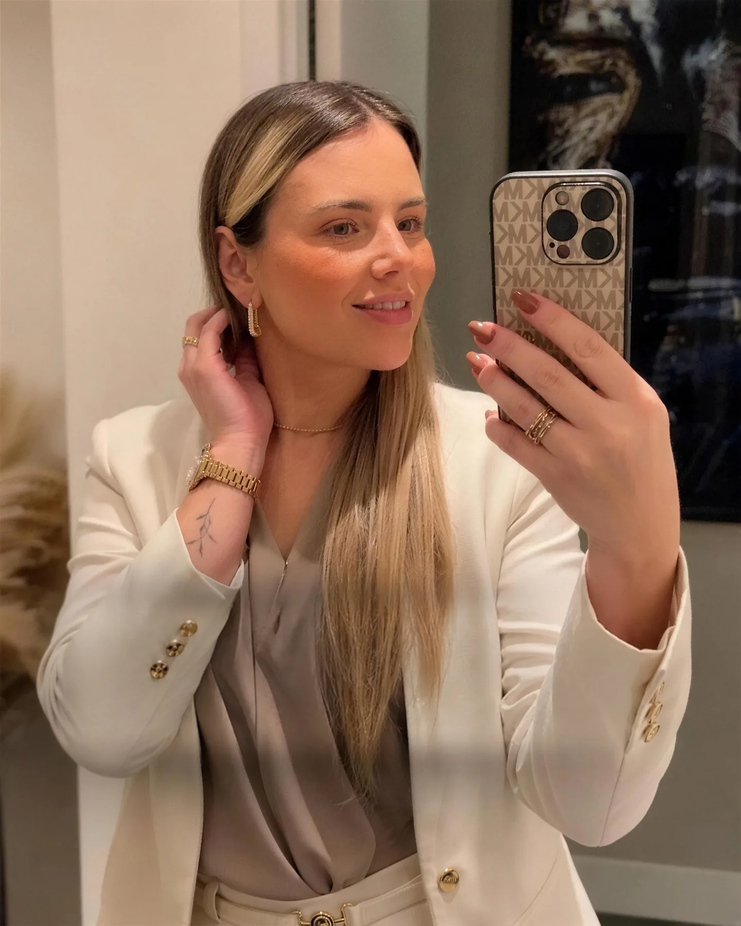 Dra. Letícia Hellen de blazer creme, sorrindo, em foto no espelho do consultório